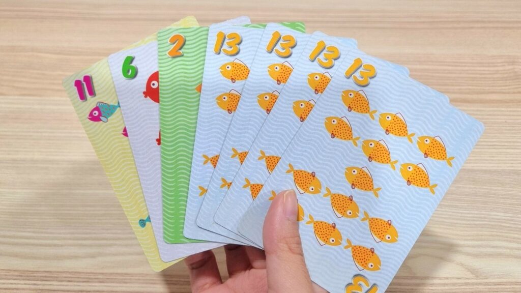 7 go fish cards in a hand with a book